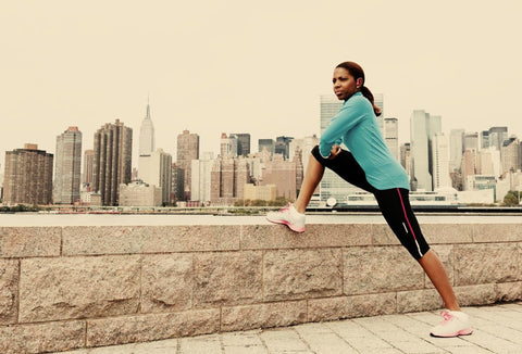 Woman stretching her leg beside a city waterfront