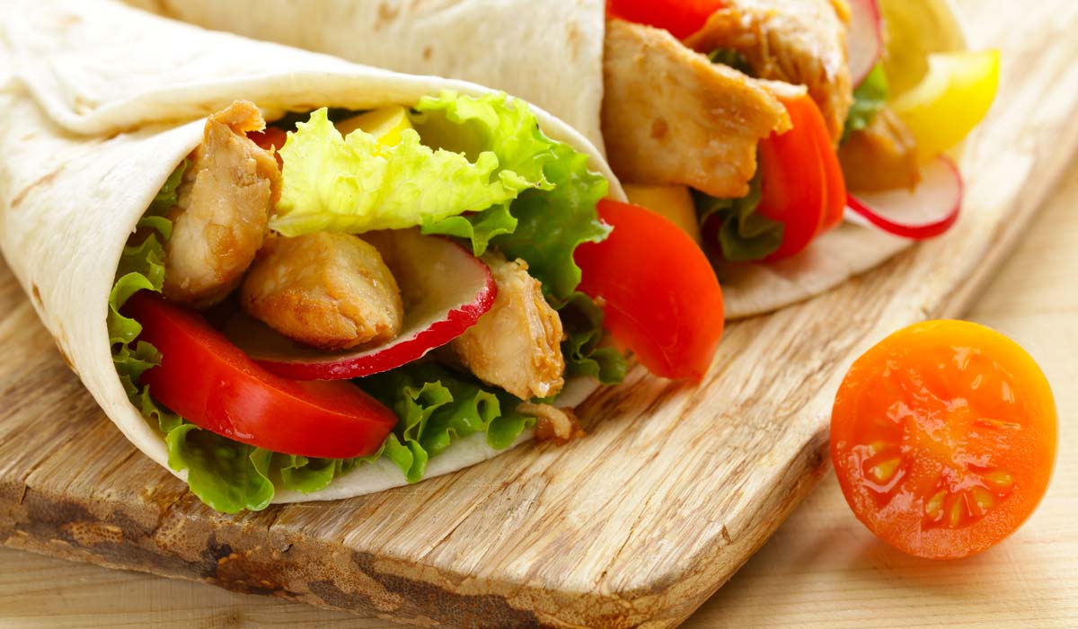 Chicken and vegetable wraps on a wooden board