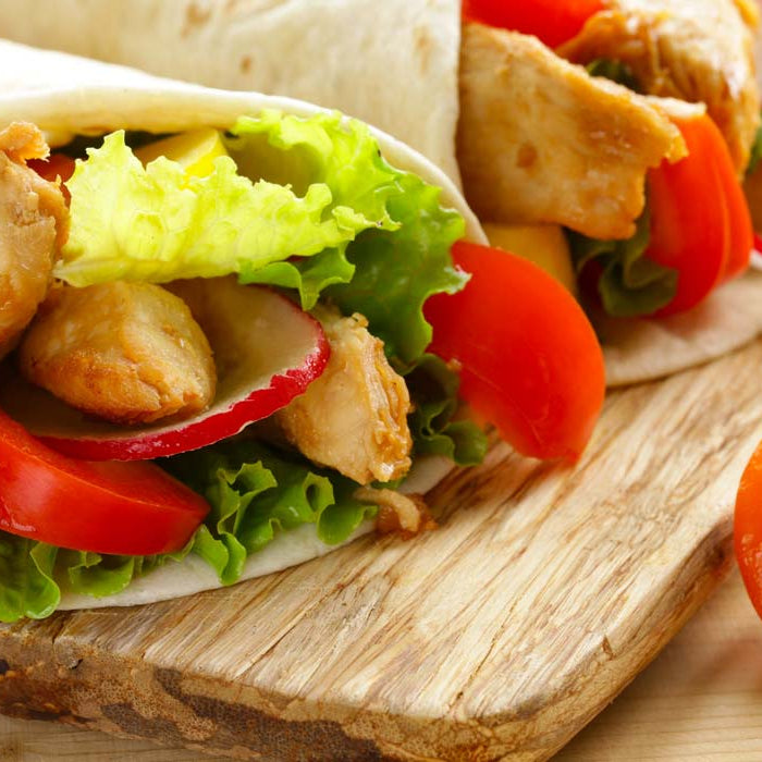 Chicken and vegetable wraps on a wooden board